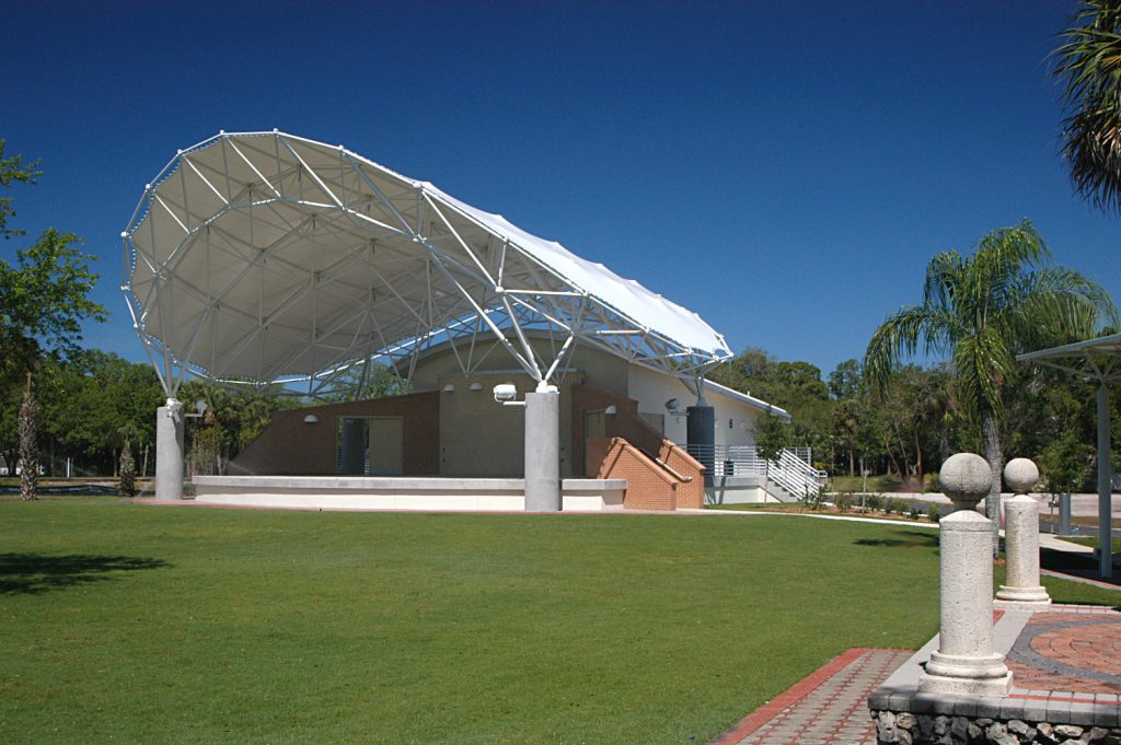 Riverside Park bandshell on a sunny day in downtown Bonita Springs, Florida with lush green lawn and shade trees